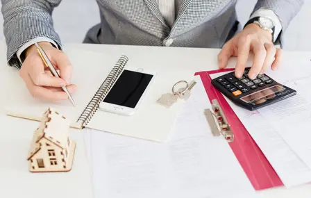 Mesa com contrato, planta do imóvel, calculadora e chaves durante análise documental