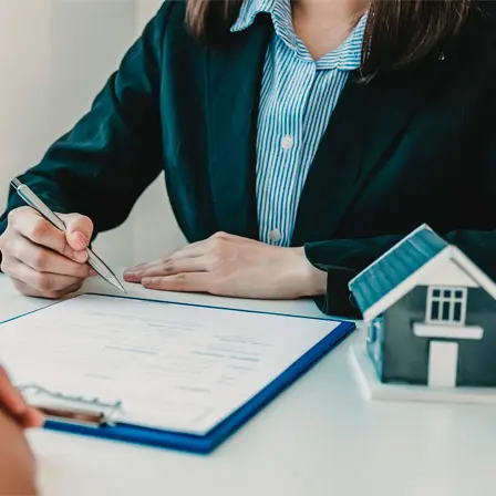 Assinatura de contrato de compra e venda de imóvel com maquete de casa sobre a mesa